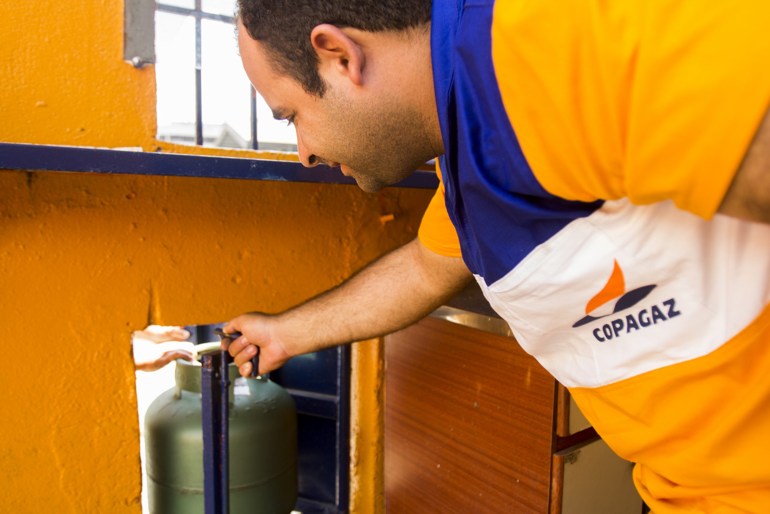 Funcionário da Copagaz instalando botijão de gás.