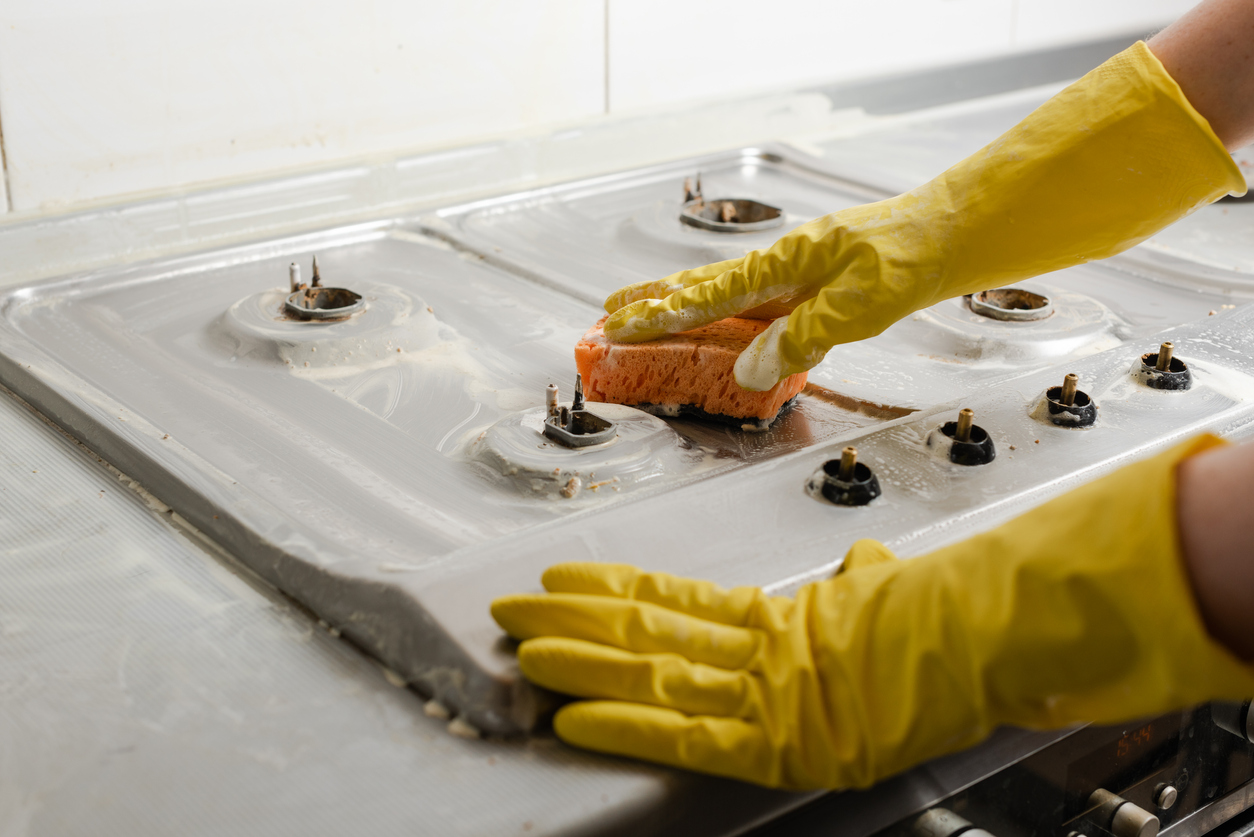 Pessoa limpando o plástico derretido do fogão